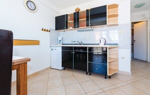 Eine kleine Küche mit einem Kühlschrank, einer Kaffeemaschine und einem Spülbecken.