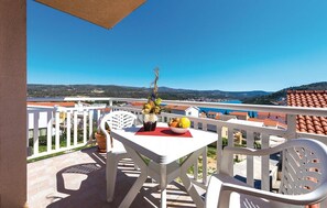 Ein Balkon mit Tisch, Stühlen, einer Blumenvase und einer Obstschale.