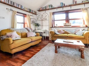 A cozy living room with two yellow sofas, a wooden coffee table, and bookshelves filled with books. - Vive House, Ribchester (Preston)
