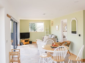 A spacious living area with a dining table, chairs, a television, and a sofa.