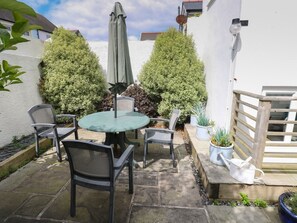 A patio with a round table and chairs, surrounded by potted plants and a wooden fence.