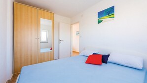 Un dormitorio con cama, armario, espejo y un cuadro en la pared.