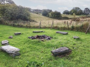 A grassy field with scattered rocks and a pile of stones. - Tyn Llwyn, Eisingrug (Talsarnau)