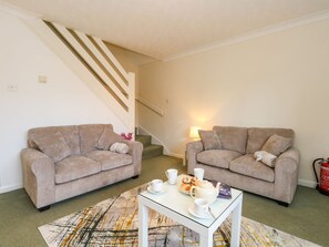 Ein Wohnzimmer mit zwei Sofas, einem Couchtisch und einer Treppe.