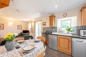 A kitchen with wooden cabinets, a tiled backsplash, a microwave, and a dishwasher. - Cwmdu Cottage, Newcastle Emlyn (Newcastle Emlyn)
