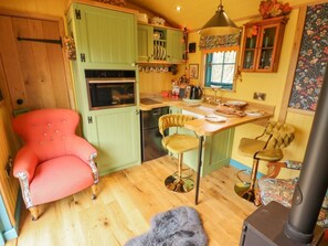 A cozy kitchen with a red chair, a wooden table, and a stove. - Catchwater rests in Keal Cotes (Spilsby)