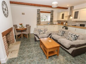 Ein Wohnzimmer mit Sofa, Couchtisch, Kamin und einem Essbereich mit Stühlen und Tisch.