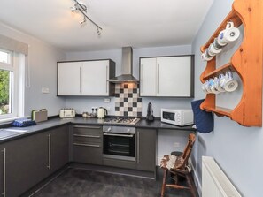 A compact kitchen with a gas stove, microwave, and checkered backsplash. - Chatelherault, Ruthwell (Dumfries)