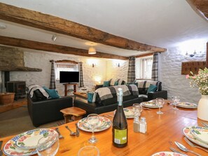 A cozy living room with a fireplace, a sofa set, a dining table set for four, and a television.