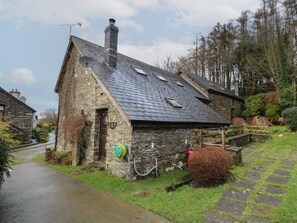 A stone building with a sloped roof, a chimney, and a small door.
