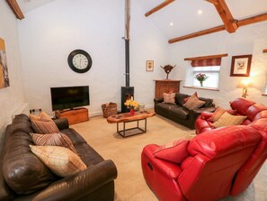 Ein Wohnzimmer mit Kamin, Sofas, einem Fernseher und einer Wanduhr.