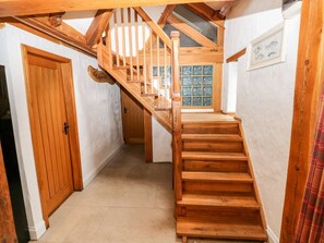 Eine Holztreppe führt zu einem erhöhten Bereich mit Blick auf ein grünes Fenster.
