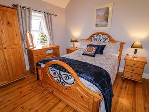 Ein Schlafzimmer mit einem hölzernen Bett, zwei Nachttischen, einem Schrank und einem Fenster mit Vorhängen.