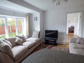 A living room with a sofa, a television, and a view of the outdoors. - The Old Clockmakers, Norwich (Norwich)