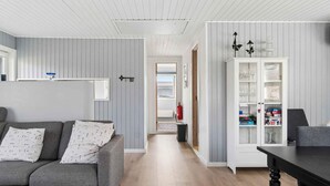 Ein modernes Wohnzimmer mit grauem Sofa, einem Holztisch und einer weißen Kommode mit Glaswaren.