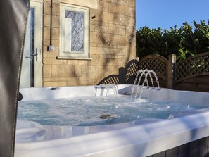 A hot tub with a wooden fence and a stone wall in the background. - Willow Cottage: A Cozy Escape (Rye)