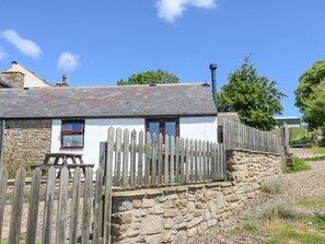 A stone-walled cottage with a wooden fence, a chimney, and a clear blue sky. - Dale View Cottage: Cozy Retreat (Hexham)