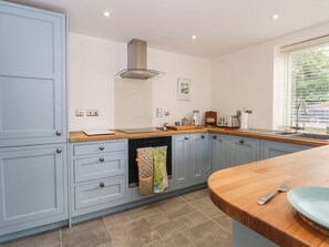 A kitchen with light blue cabinets, a wooden countertop, a built-in oven, and a window with blinds. - Kestrel, Tilston: A Charming Retreat (Malpas)