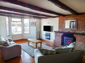 A living room with a fireplace, a television, and a sofa. - Smugglers' Cottage, Marske-By-The-Sea (Redcar)