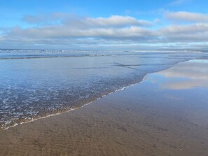 A beach with a wide expanse of sand and gentle waves.