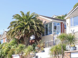 Ein Wohnhaus mit einer großen Palme, einem Anbau und einer Ziegel-Fassade.