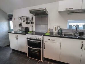 Eine moderne Küche mit weißen Schränken, einem Backofen, einem Herd, einer Spüle und einem Fenster mit Blick.