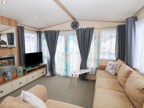 A modern living room with a flat-screen TV, sofa, and a small table. - 50, Foxburrow Hang, in Norfolk (Great Yarmouth)