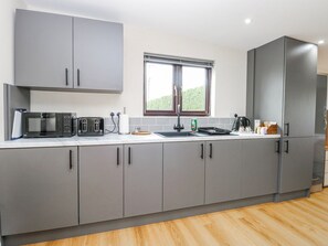 A modern kitchen with grey cabinets, a microwave, toaster, and a sink. - Aloe Lodge Retreat Near Heath Fm (Diss)