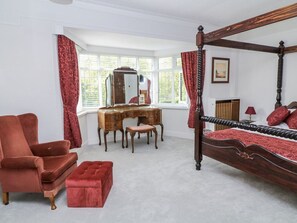 A bedroom with a four-poster bed, a wooden desk, a chair, and a red ottoman. - Bentfield House, Whiston (Rotherham)