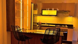 Una cocina moderna con una isla central, taburetes de bar e iluminación colgante.