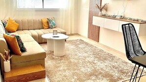 Una sala de estar moderna con un sofá, una mesa de centro y un televisor montado en la pared.