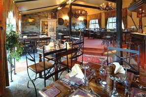 A restaurant with stone walls, wooden furniture, and a red carpet. - The Smithy: A Cozy Retreat (Wooler)