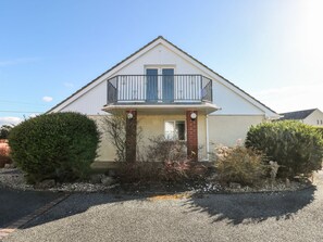 A two-story house with a balcony, a small front porch, and a gravel driveway. - Meadow View, Letterston (Haverfordwest)