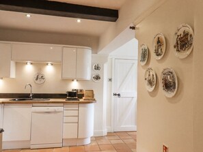 A kitchen with white cabinets, a sink, and a dishwasher. There are decorative plates on the wall. - HOP HOUSE: Cozy Retreat with WiFi (Hastings)