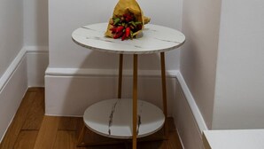 Una mesa pequeña y blanca con una bolsa de papel que contiene pimientos rojos y verdes.