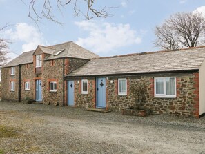 A stone building with multiple doors and windows, a gravel driveway, and a clear sky. - The Loft, Holsworthy (Holsworthy)