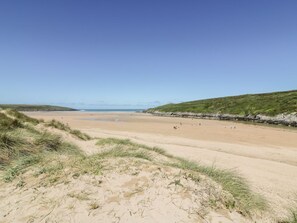 Una playa con dunas de arena y cielo despejado.