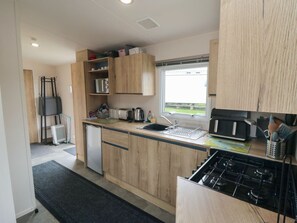 Eine moderne Küche mit Holzausbau, einer eingebauten Mikrowelle, einem Gasherd und einem Fenster für natürliches Licht.