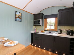 A kitchen with a microwave, sink, and dark cabinets. - Dam View Shepherds Hut, Rhayader (Rhayader)