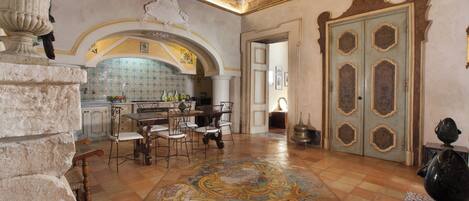 A dining area with a tiled floor, a chandelier, and a large ornate mirror.