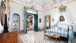 Een kamer met een bed, een dressoir, een spiegel en een deur naar een andere kamer.