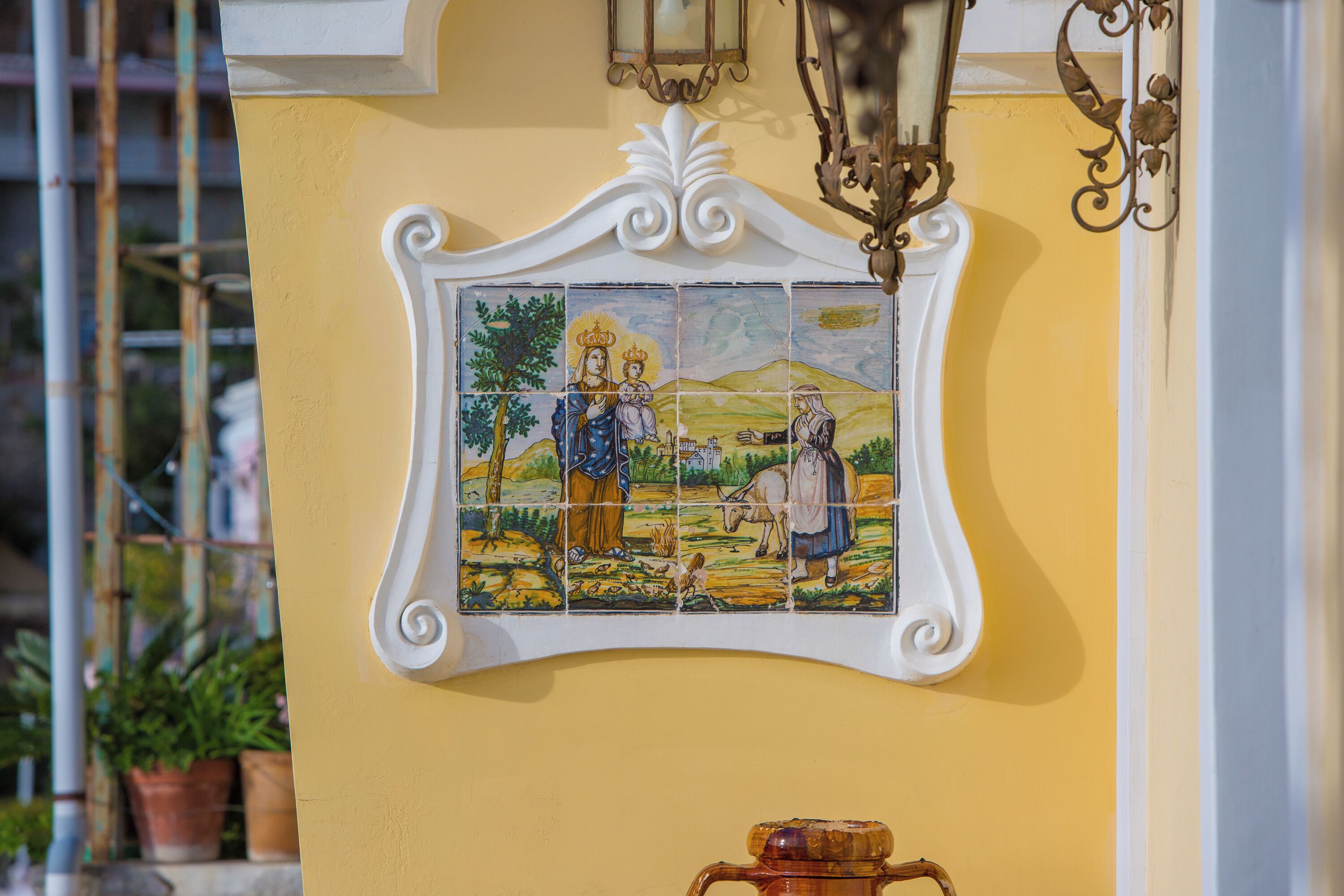 Een muur met een decoratief tegelpaneel en een hangende lamp.