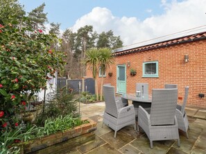 A brick house with a tiled roof, a green door, and a patio with wicker furniture. - Primose Cottage, Cromer, Norfolk (Cromer)