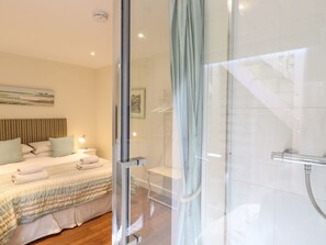 A modern hotel room with a glass shower enclosure, a neatly made bed with a striped duvet, and a bedside table with a lamp. - Kinsale, Broadstairs (Broadstairs)