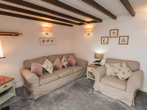 A living room with two beige sofas, a wooden coffee table, and wall-mounted lamps.
