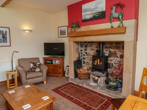 A cozy living room with a stone fireplace, a television, a sofa, and a coffee table.