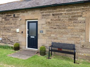 A stone building with a black door, a bench, and a sign reading 'FOLLY VIEW.'
