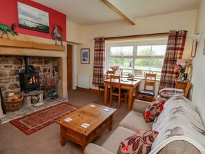 A cozy living room with a stone fireplace, a dining area, and a sofa with floral cushions.