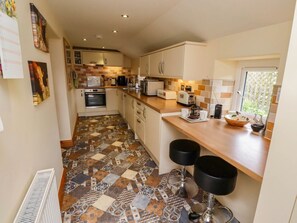 A kitchen with a patterned floor, a window, and two bar stools.