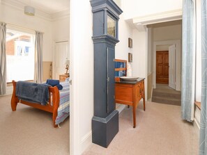 A bedroom with a bed, a dresser, a mirror, and a window with curtains. - Lancaster House, Sandown (Sandown)